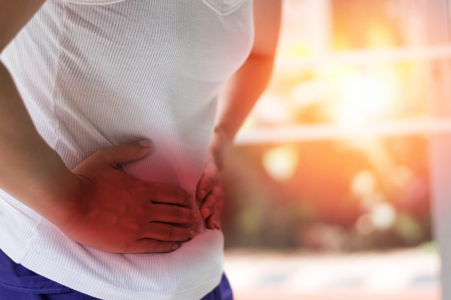 Person clutching lower abdomen in pain, illustrating hernia treatment in Singapore with modern surgical and recovery options