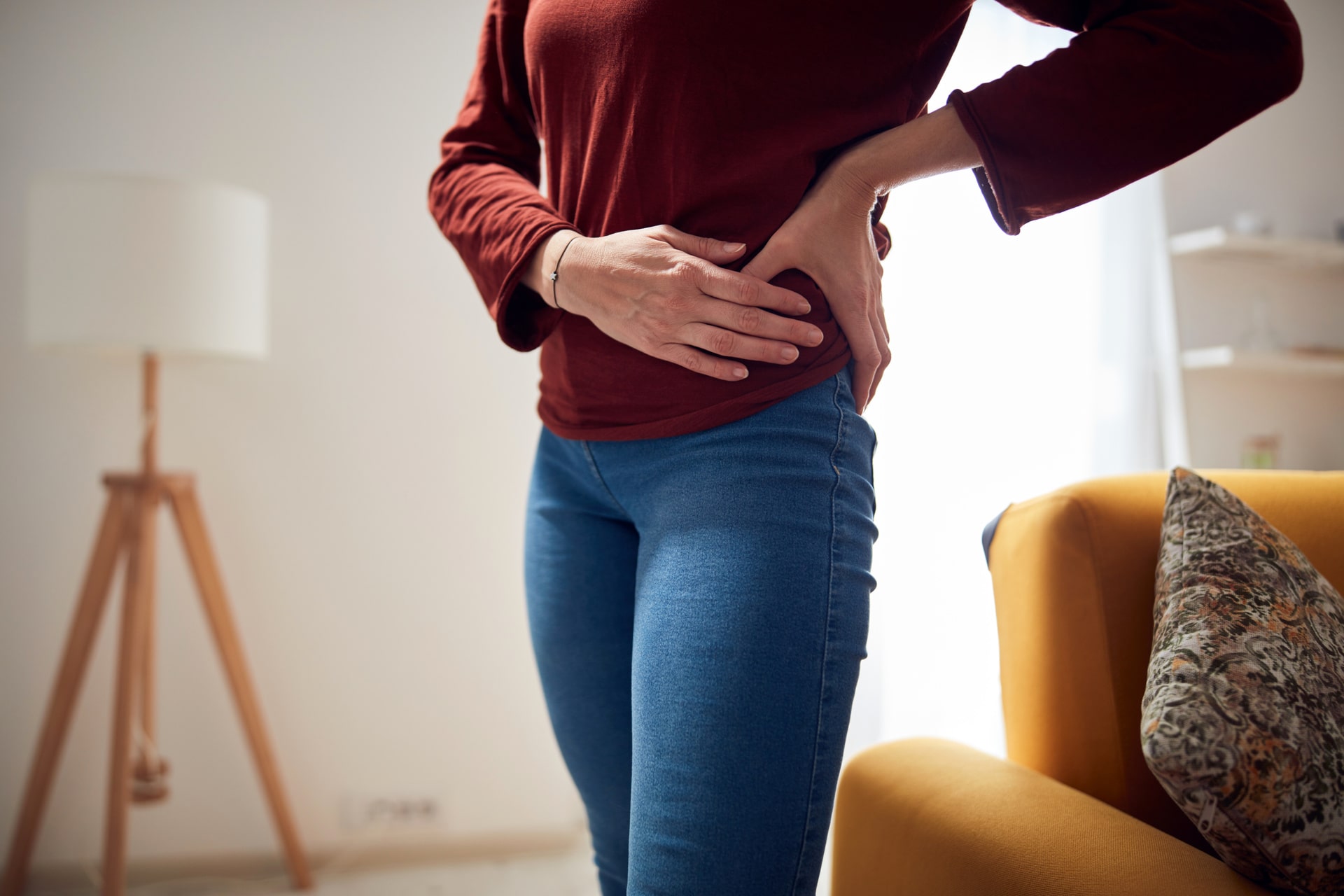 Woman holding her side in pain, representing discomfort after hernia repair in Singapore.